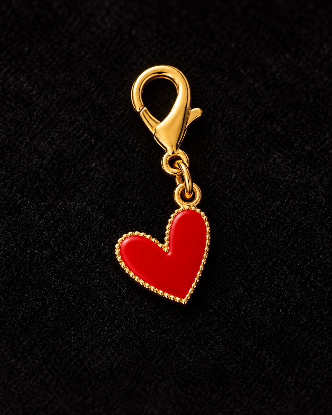 Charm AXION cuore rosso con moschettone dorato, su sfondo nero.
