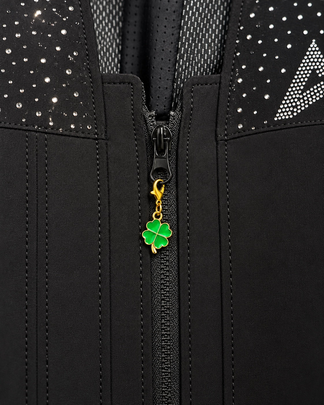 Charm AXION quadrifoglio verde con moschettone dorato, agganciato a un tirazip nero.