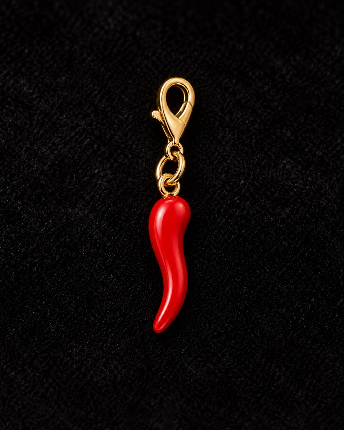 
Charm AXION peperoncino rosso con moschettone dorato, su sfondo nero.