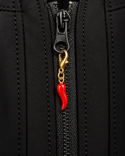 
Charm AXION peperoncino rosso con moschettone dorato, agganciato a un tirazip nero.