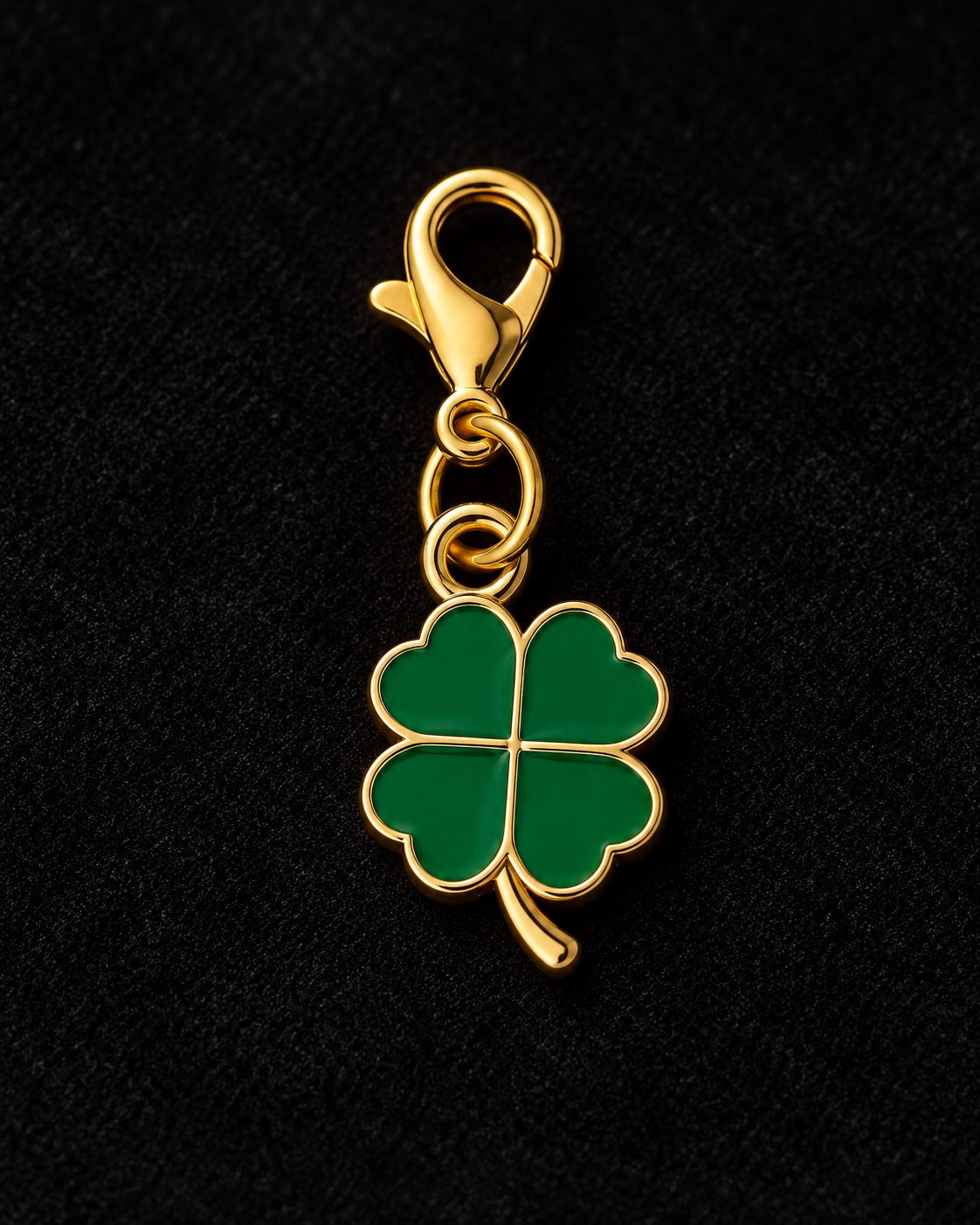 
Charm AXION quadrifoglio verde con moschettone dorato, su sfondo nero.