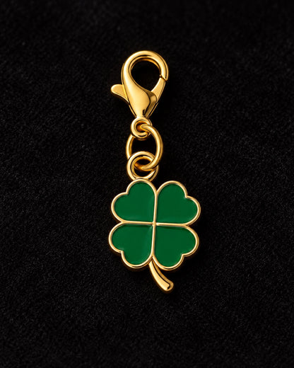 
Charm AXION quadrifoglio verde con moschettone dorato, su sfondo nero.